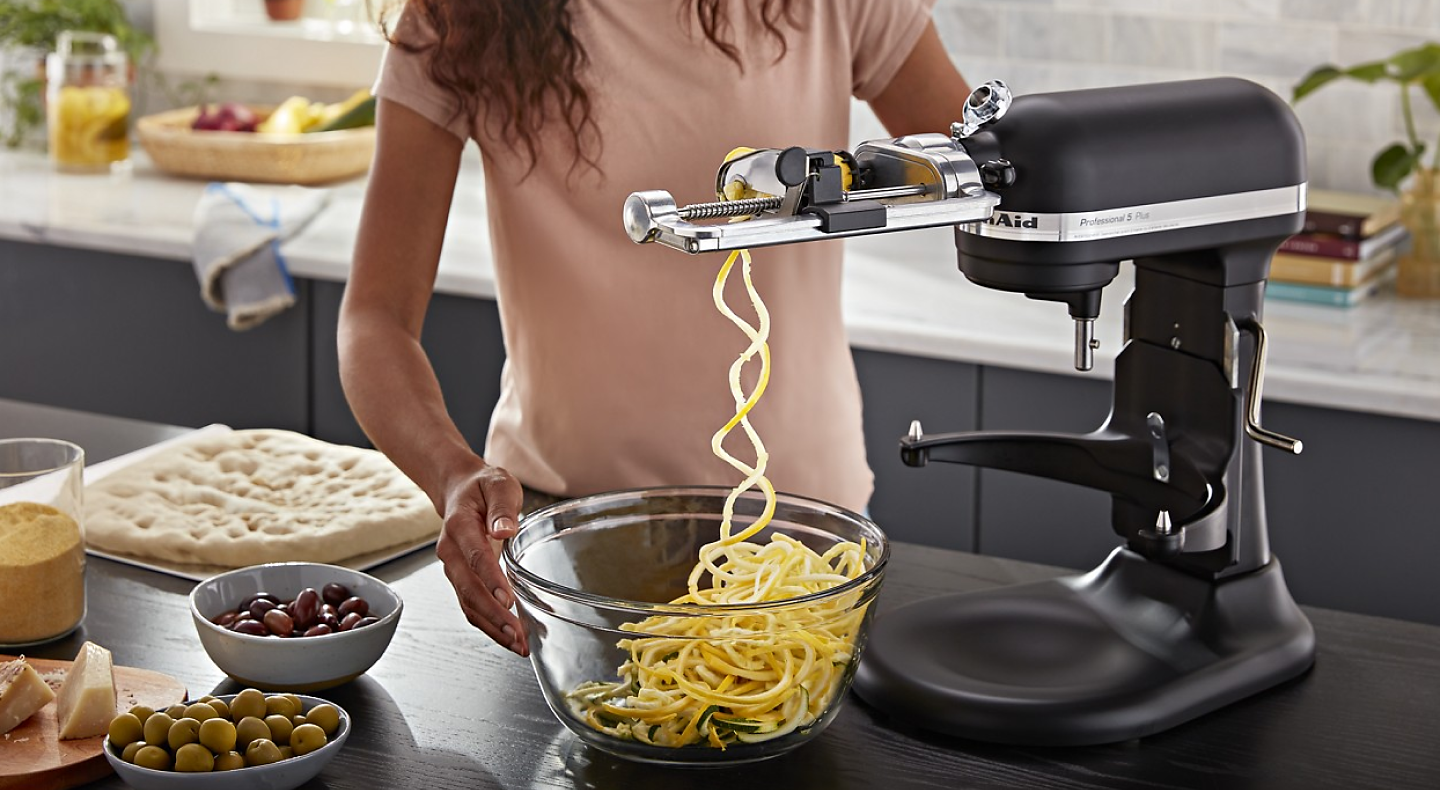 Woman creating veggie noodles with KitchenAid® mixer and spiralizer attachment