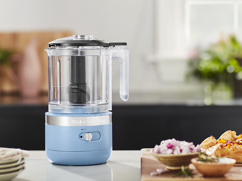A KitchenAid® food processor with ingredients sitting next to it