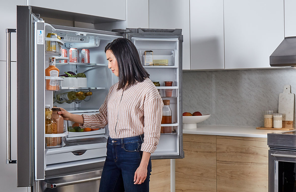Woman removing a carton of chocolate milk from the side shelves of a refrigerator Woman removing a carton of chocolate milk from the side shelves of a refrigerator