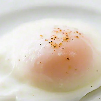 Close up of a poached egg topped with salt and pepper