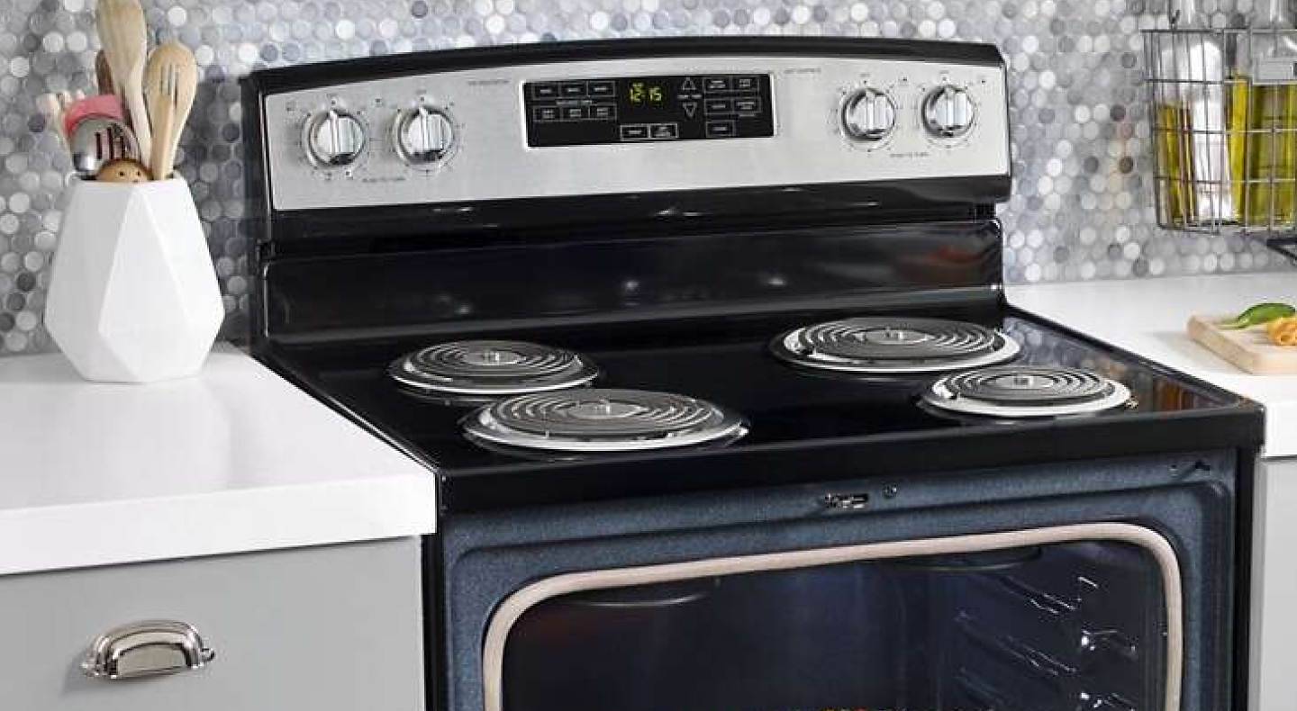 Black electric stove with coil burners in front of a gray and white backsplash