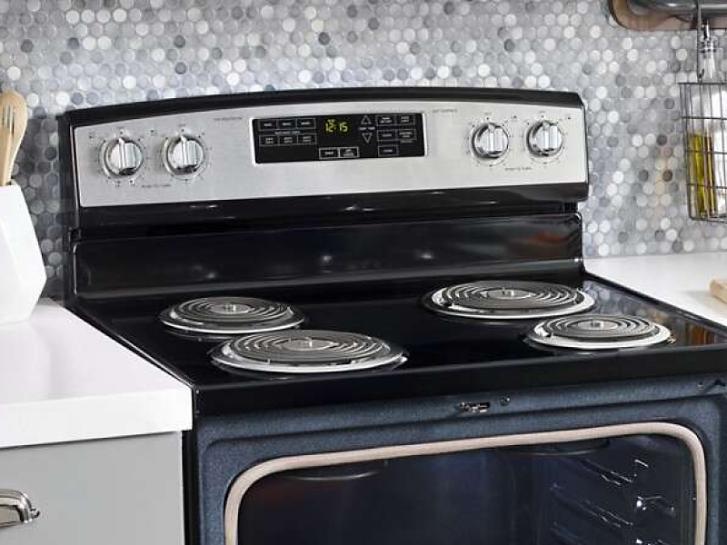 Black electric stove with coil burners in front of a gray and white backsplash