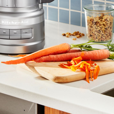 Carrots on a cutting board next to a KitchenAid® food processor