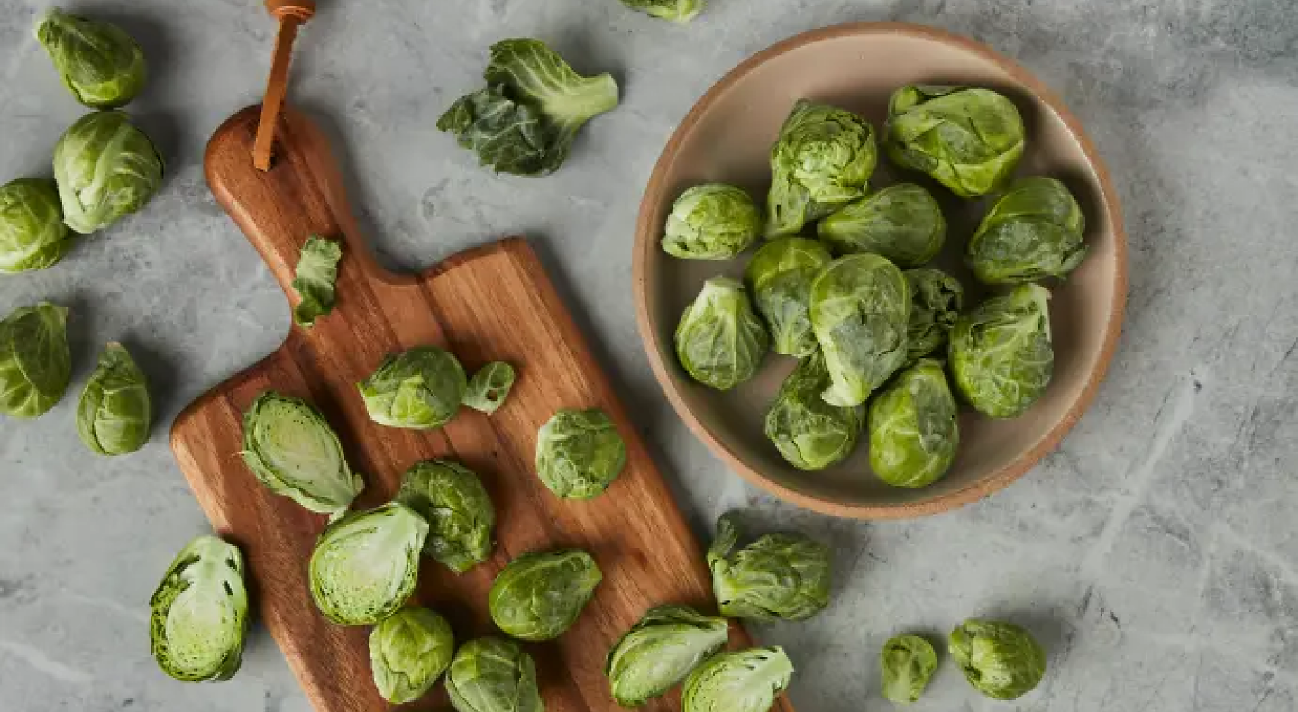 Bowl of Brussels sprouts next to sliced Brussels sprouts on a cutting board