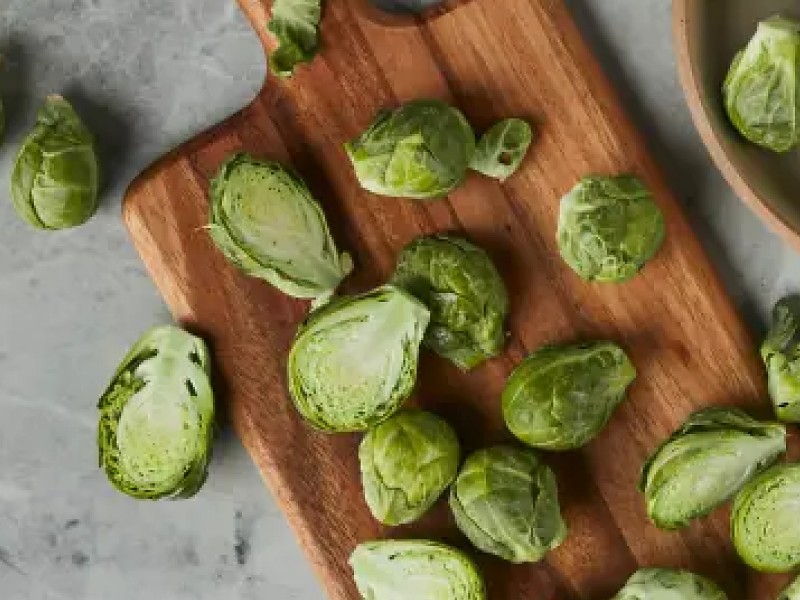 Bowl of brussel sprouts next to sliced brussel sprouts on a cutting board