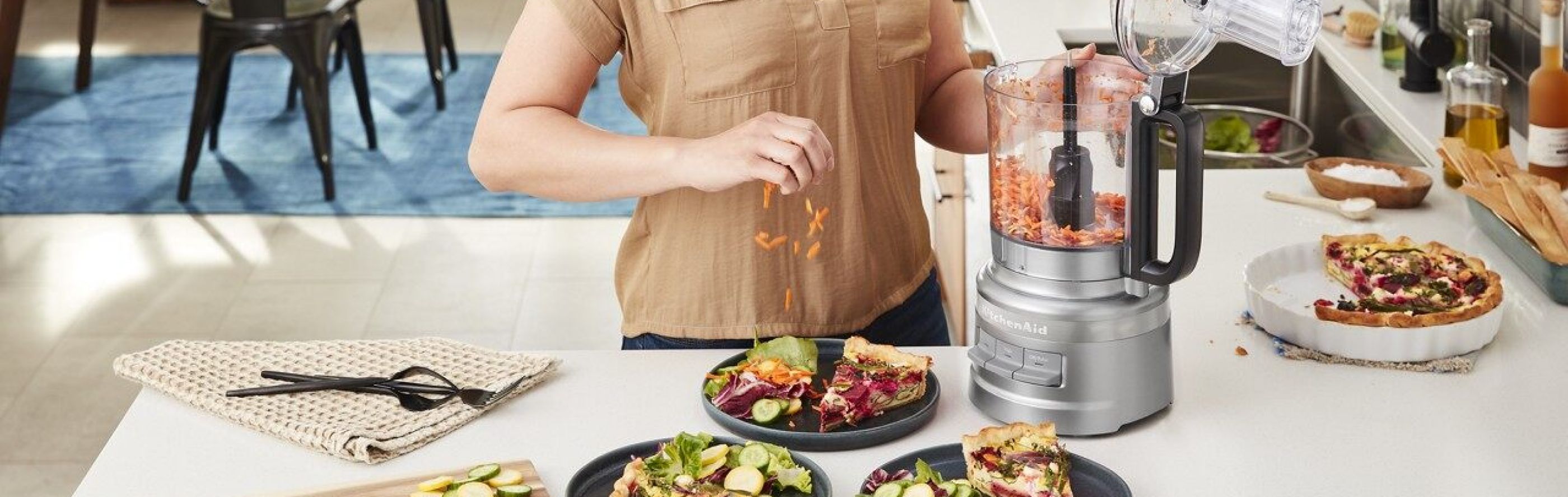Woman shredding vegetables for a salad with a KitchenAid® food processor