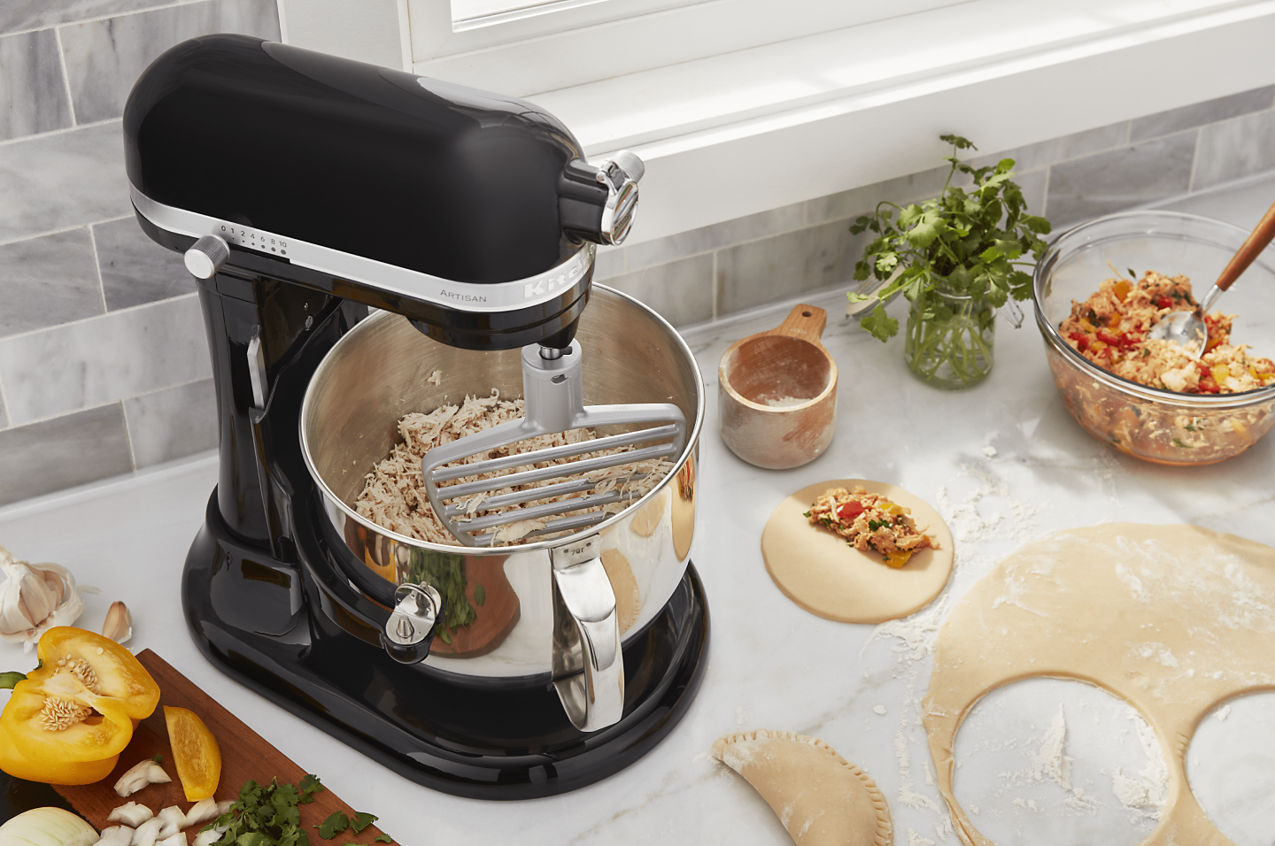 KitchenAid® stand mixer on a modern kitchen counter shredding cooked chicken. KitchenAid® stand mixer on a modern kitchen counter shredding cooked chicken.