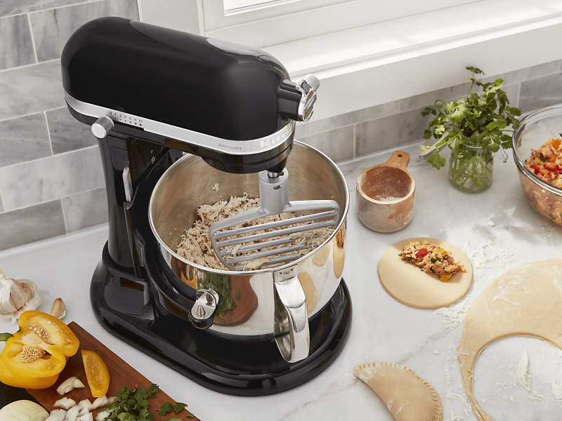 KitchenAid® stand mixer on a modern kitchen counter shredding cooked chicken. KitchenAid® stand mixer on a modern kitchen counter shredding cooked chicken.