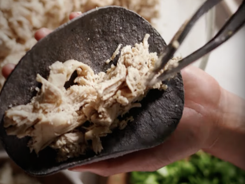Shredded chicken on a tortilla.