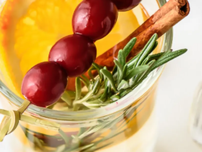 Drink garnished with cranberries, cinnamon and fresh rosemary