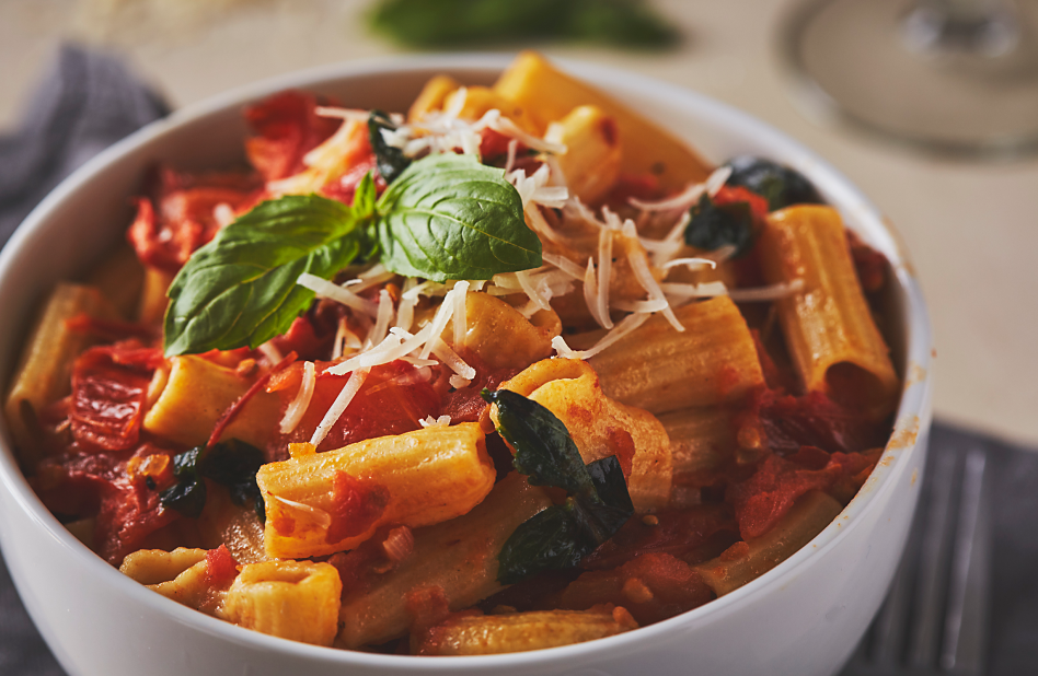 A bowl of rigatoni pasta with fresh tomato sauce, basil and cheese