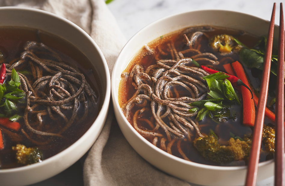 A bowl of buckwheat noodles in an Asian beef broth