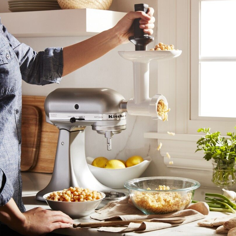 A person using a mini KitchenAid® stand mixer and shredding attachment.