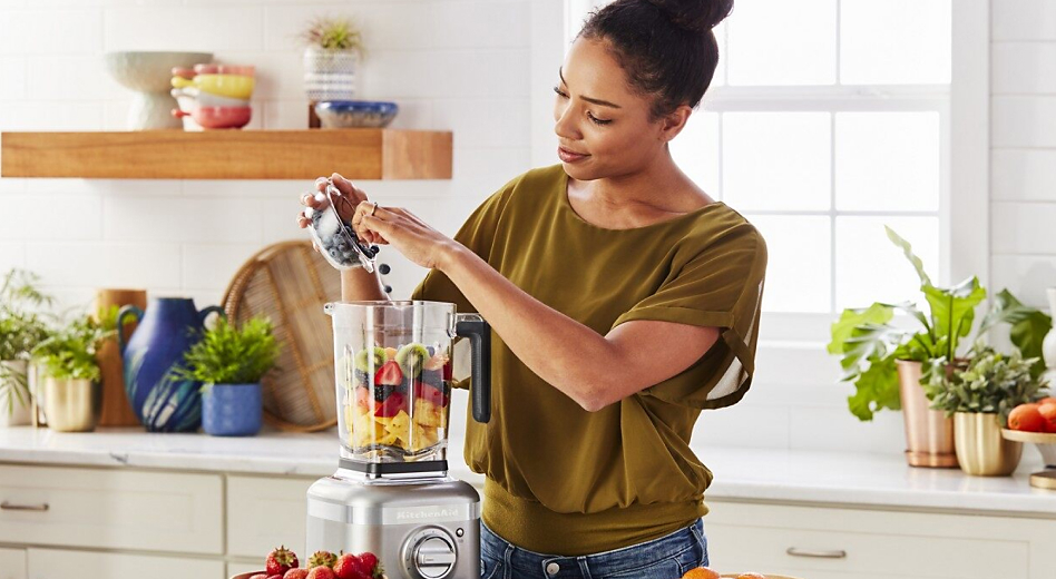 Woman preparing a fruit smoothie with a KitchenAid® blender