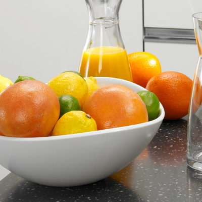 Freshly squeezed orange juice next to a bowl of fruit