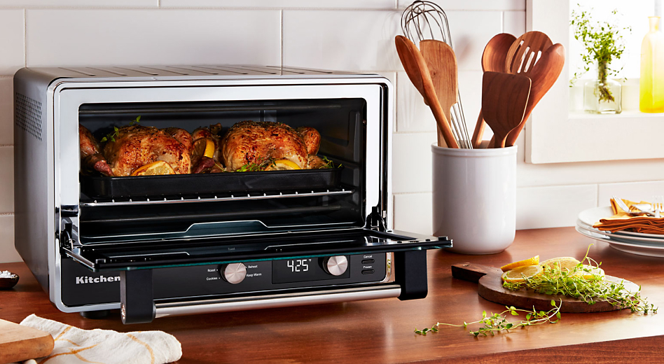 Two whole roasted chickens and greens cooked inside a KitchenAid® countertop oven