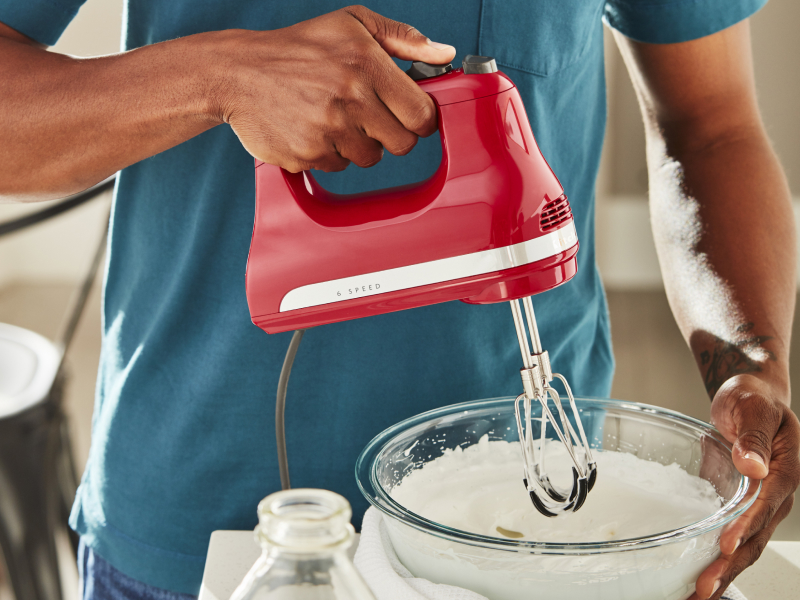 Person using KitchenAid® hand mixer over bowl of batter