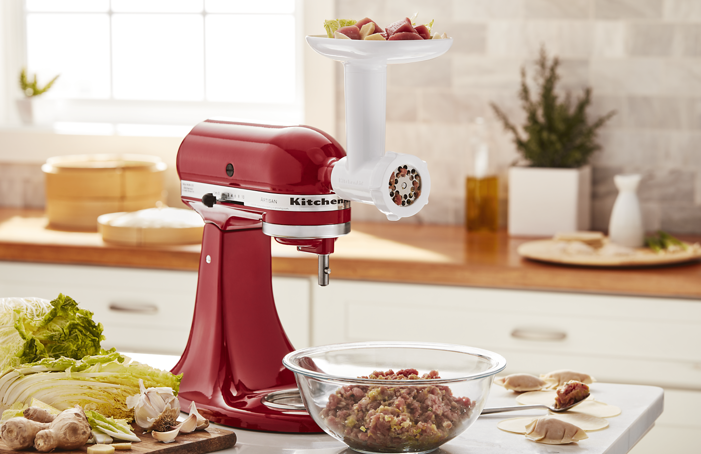 Red KitchenAid® Stand Mixer with white food grinder attachment grinding meat