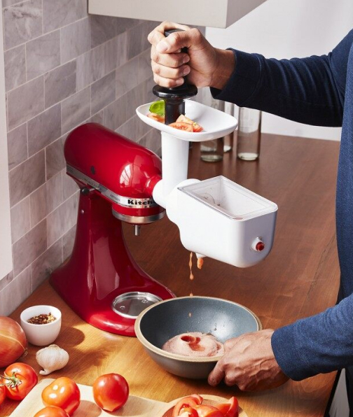 Person feeding food through meat grinder attachment with food pusher