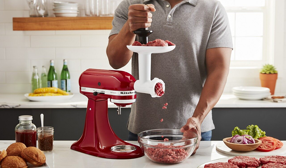 Man grinding meat for burgers using the KitchenAid® food grinder attachment