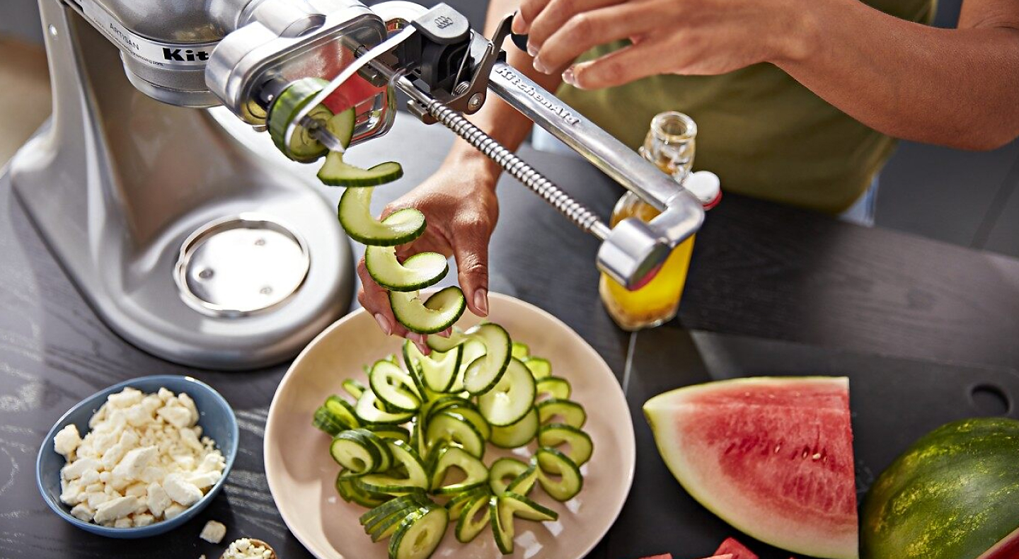 Person using 7 Blade Spiralizer Plus with Peel, Core and Slice attachment