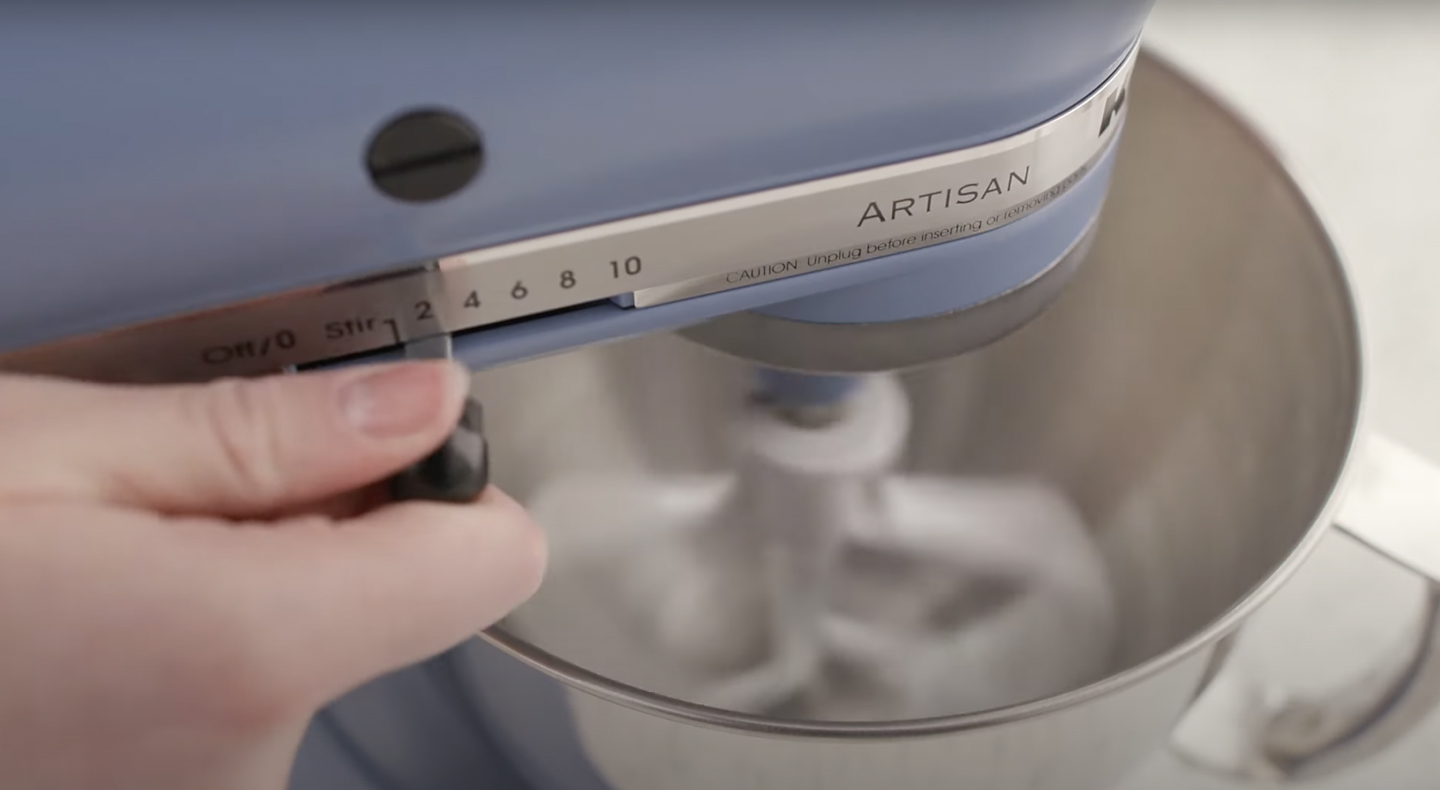 Person adjusting speed of blue KitchenAid® stand mixer