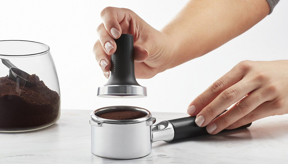 Hand tamping espresso grounds in a portafilter
