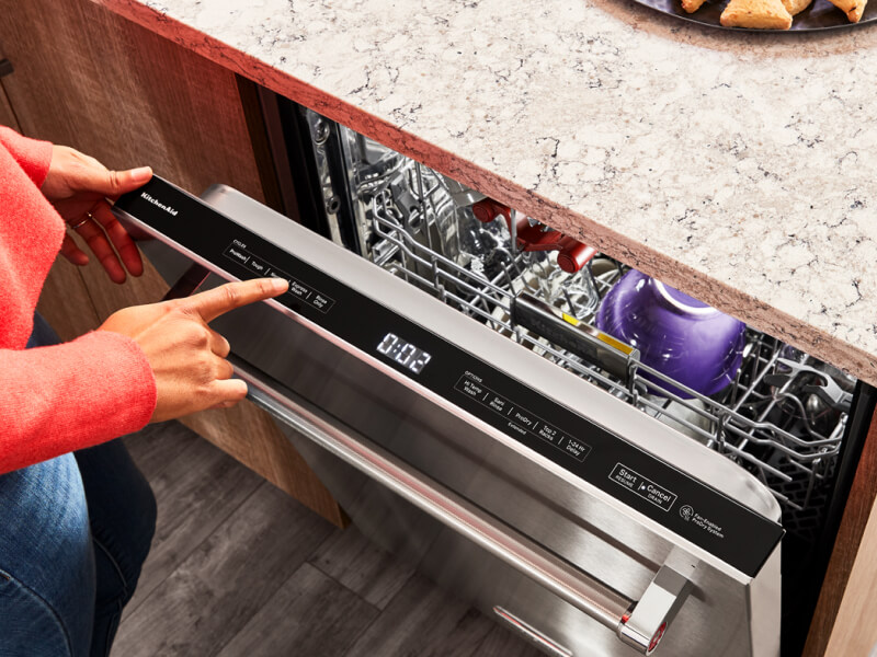 Person selecting settings on a top dishwasher control panel