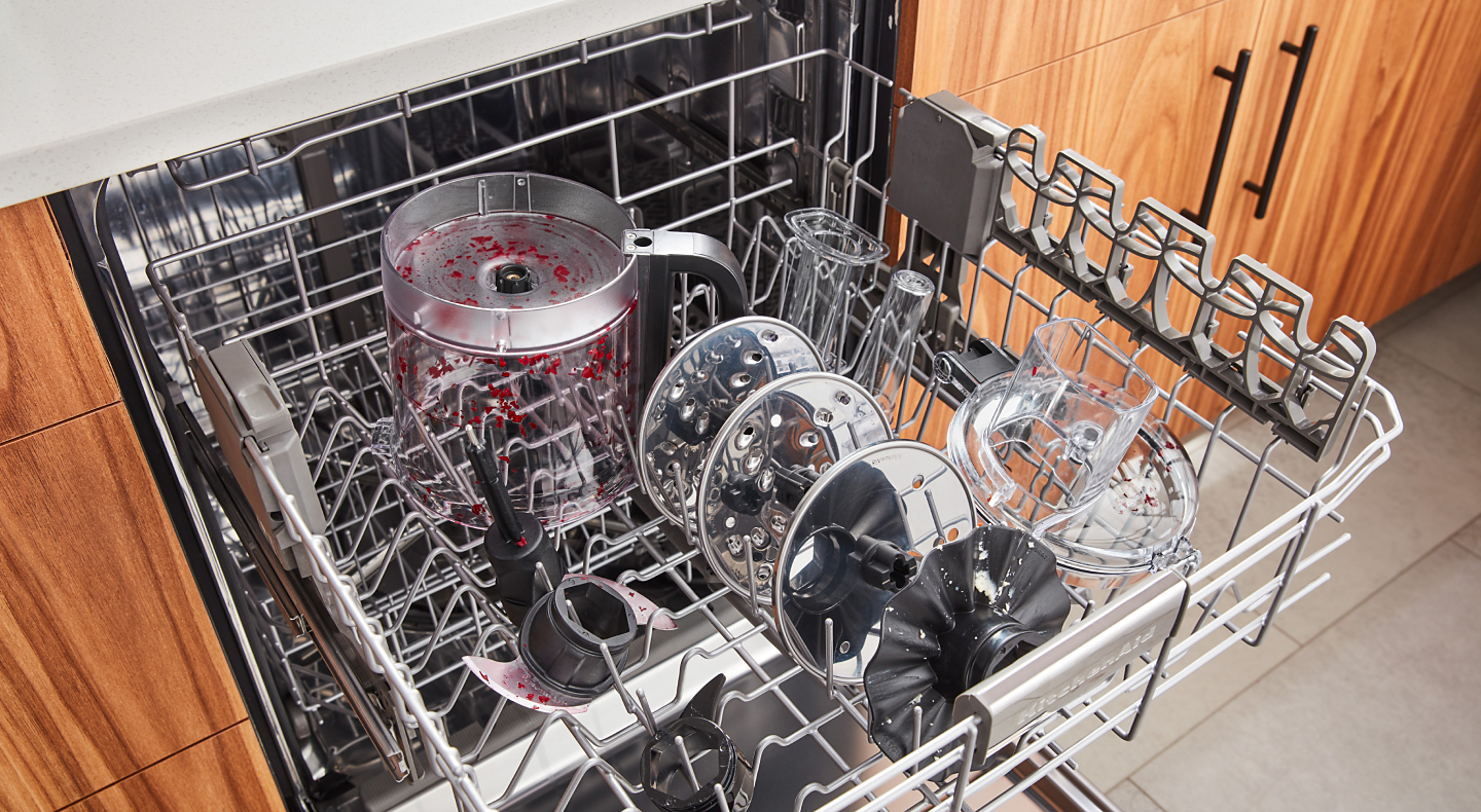 Stained food processor parts in open dishwasher rack