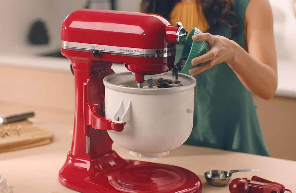 Woman pouring chocolate chips into KitchenAid® Ice Cream Maker bowl