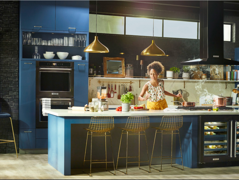 Woman cooking in a kitchen with black stainless steel KitchenAid® appliances