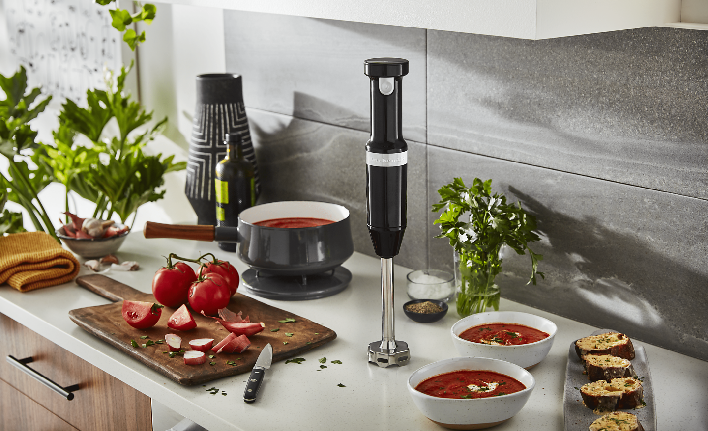 Tomato soup cooking next to an immersion blender