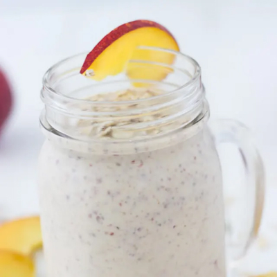 Smoothie in a mason jar with a peach on the rim