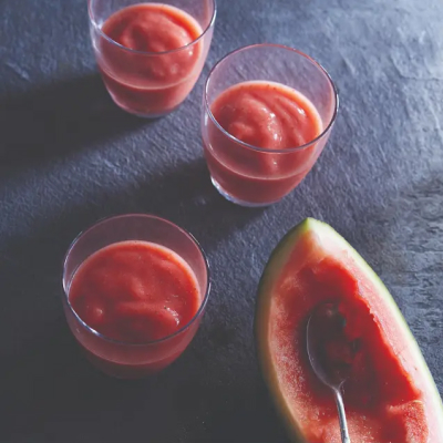 Three glasses of pink smoothie near a watermelon rind