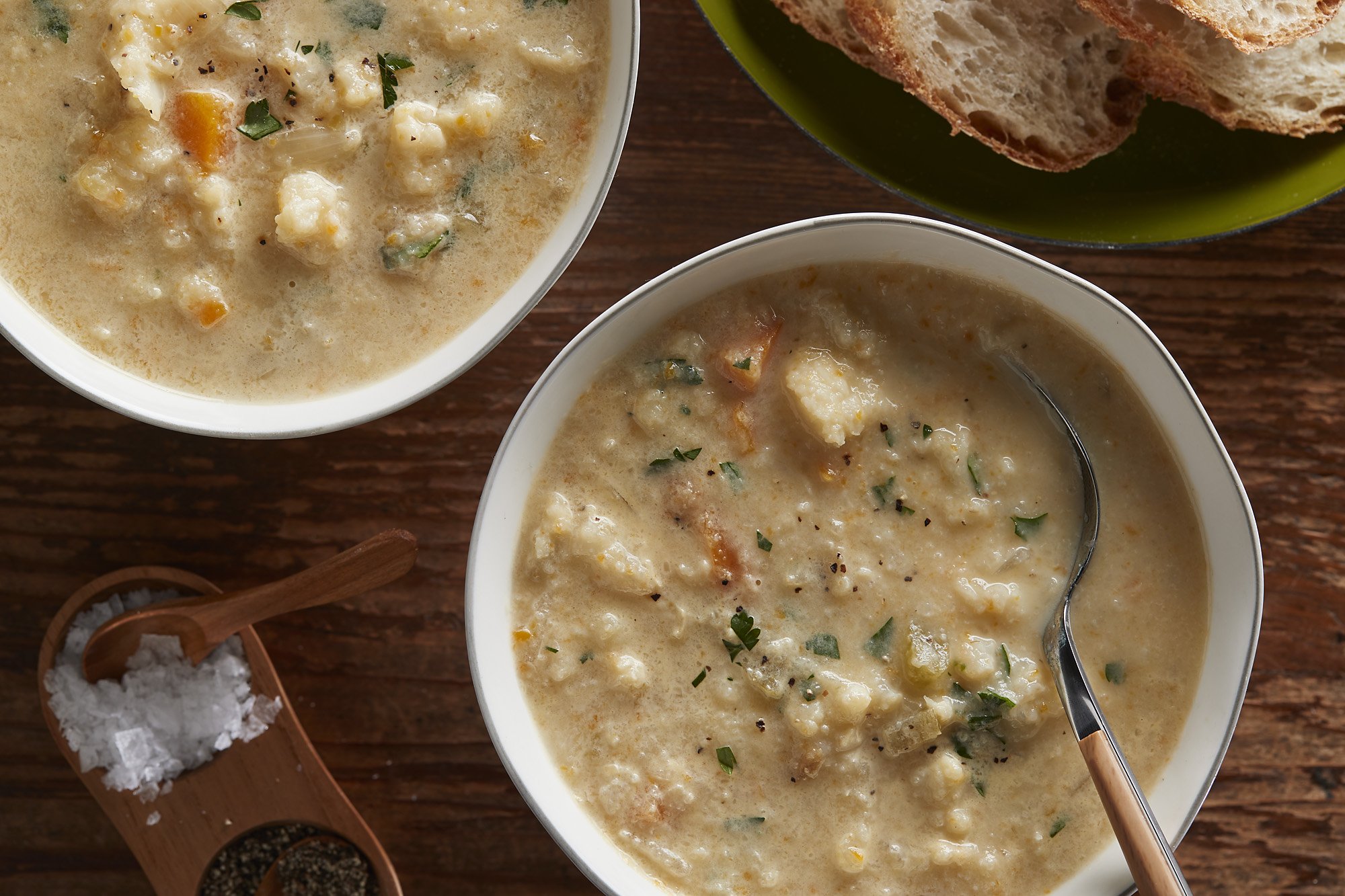 Bowls of cauliflower soup next to small containers of salt and pepper