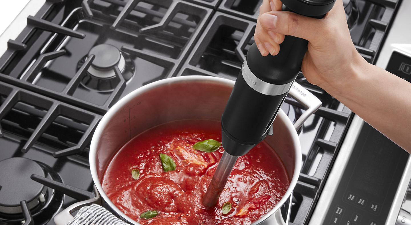 Person blending marinara with immersion blender