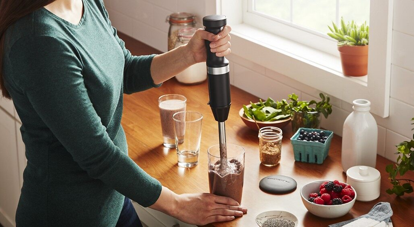 Person blending smoothie with immersion blender