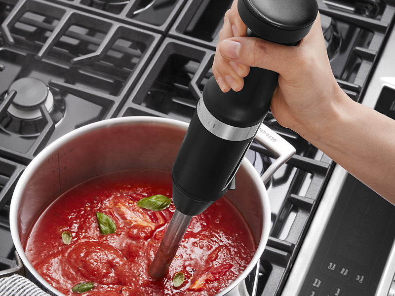 Person blending marinara with immersion blender