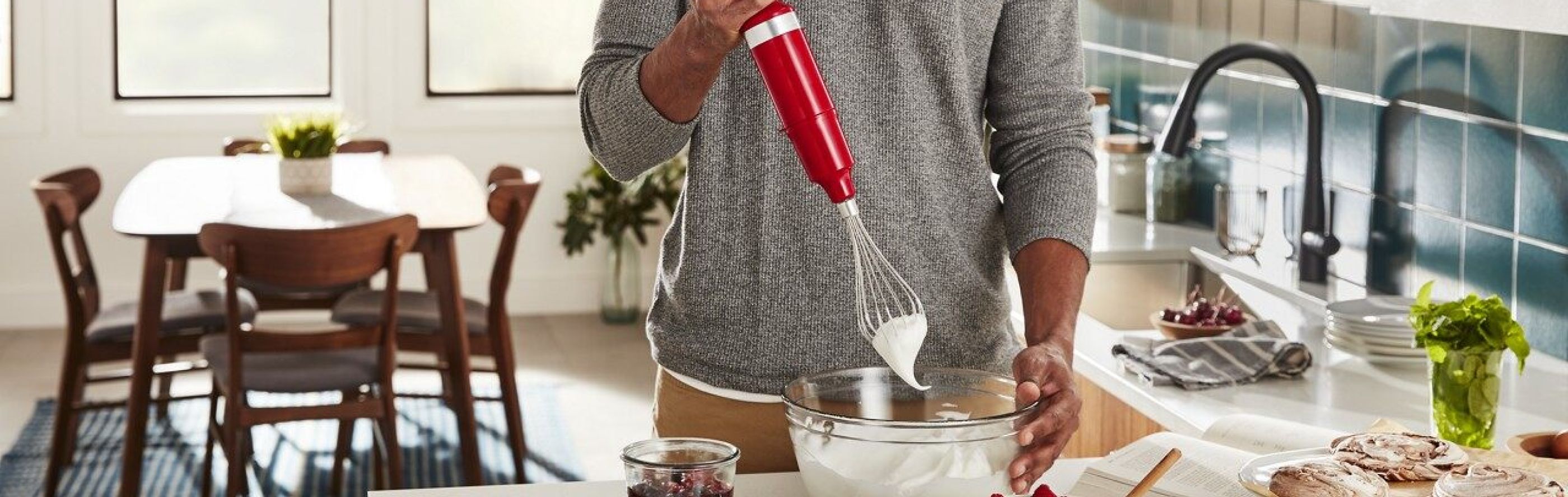 Person using red KitchenAid® immersion blender with whisk