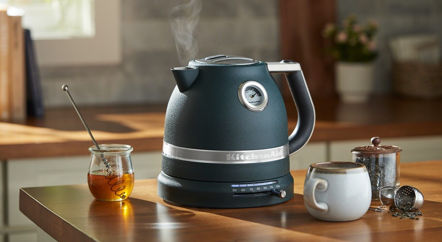 Black KitchenAid® electric kettle next to tea accessories and honey