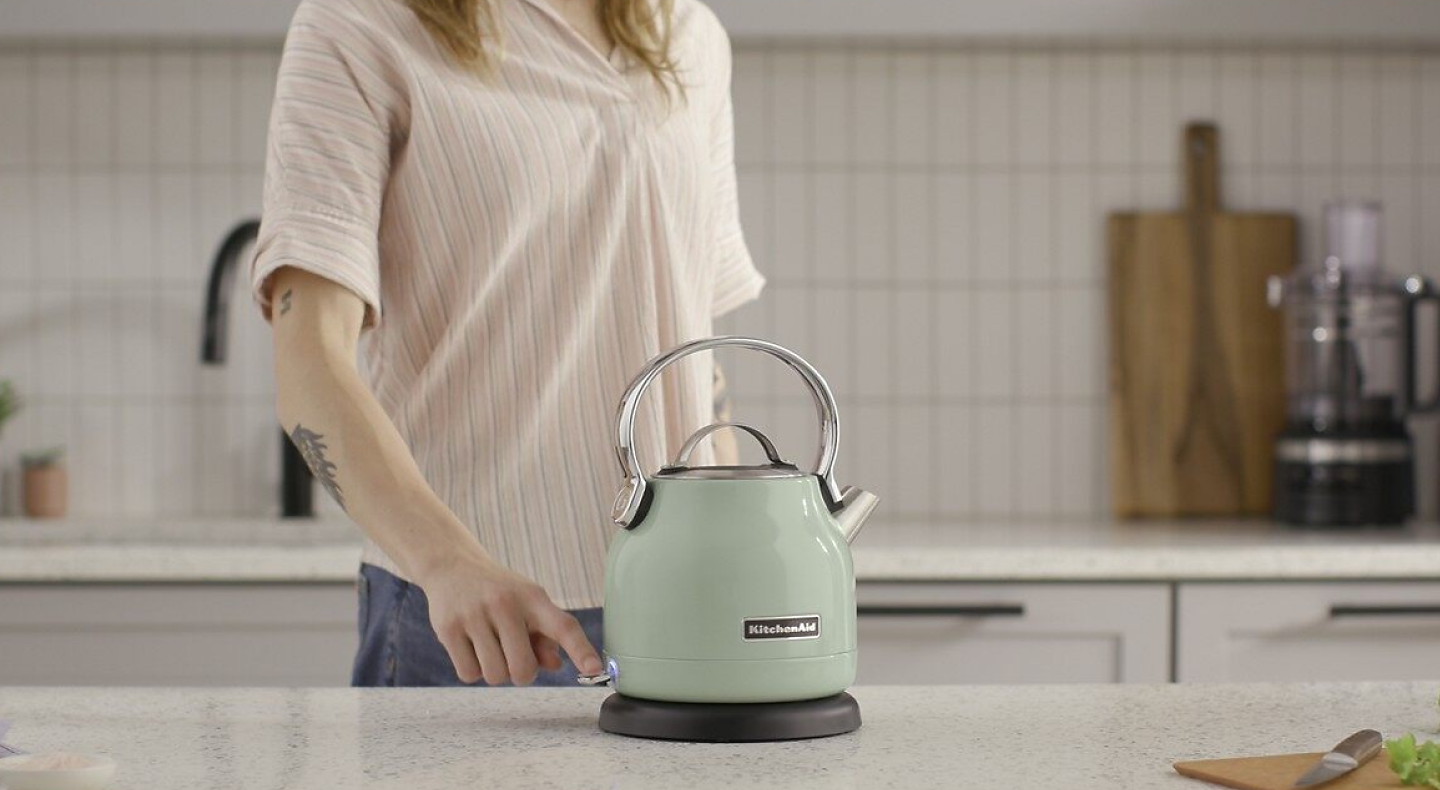 Woman standing by a green KitchenAid® electric kettle