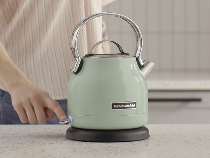 Woman standing by a green KitchenAid® electric kettle