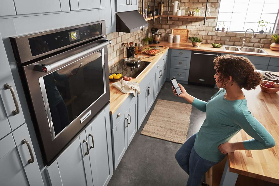 Woman on phone in front of wall oven