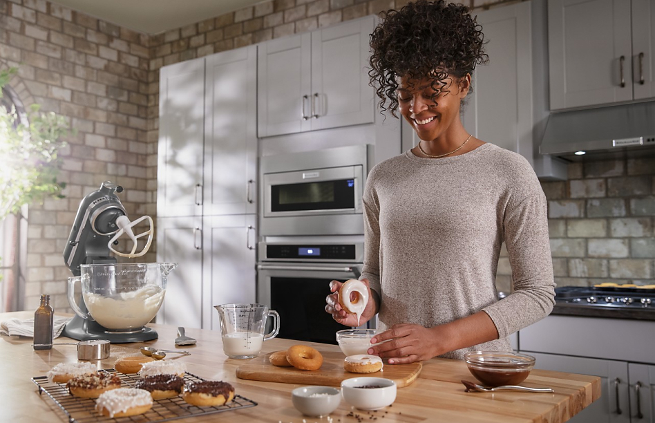 Smiling woman making donuts with a stand mixer in kitchen