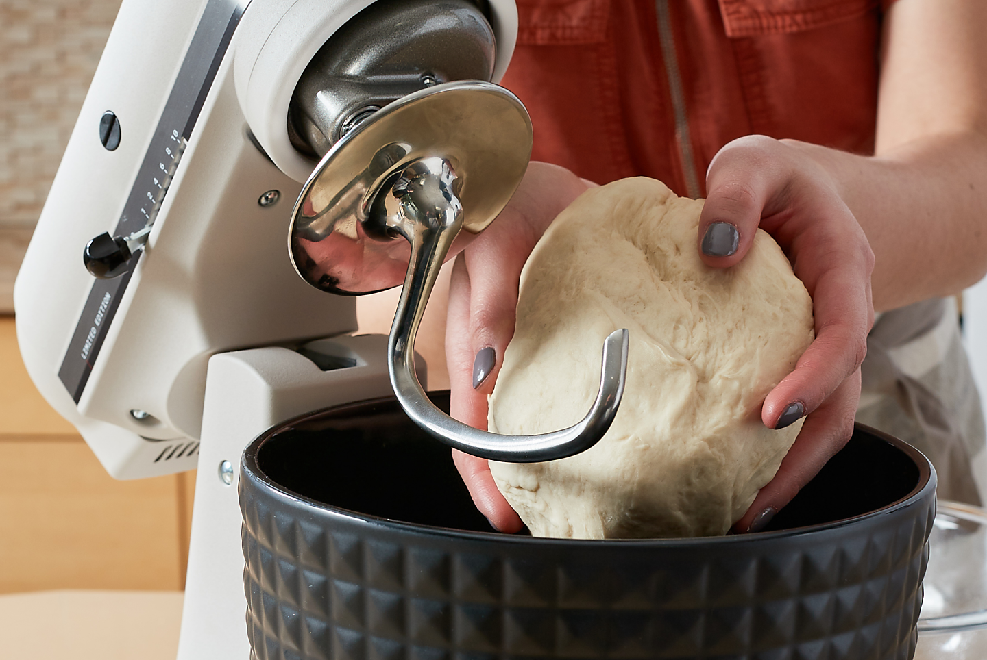 Woman removing a ball of dough from a KitchenAid® stand mixer