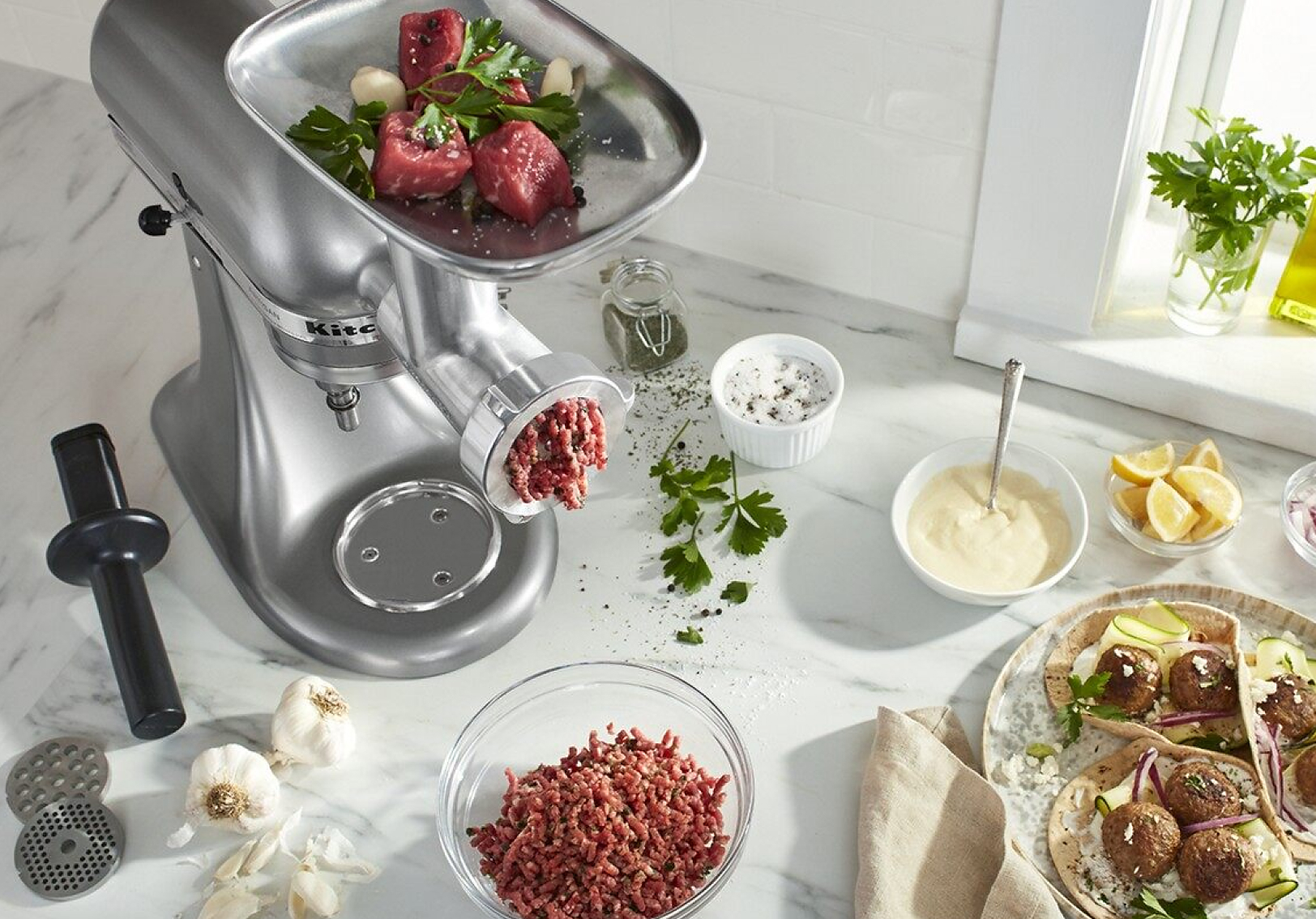 Silver stand mixer with a meat grinder attachment grinding beef