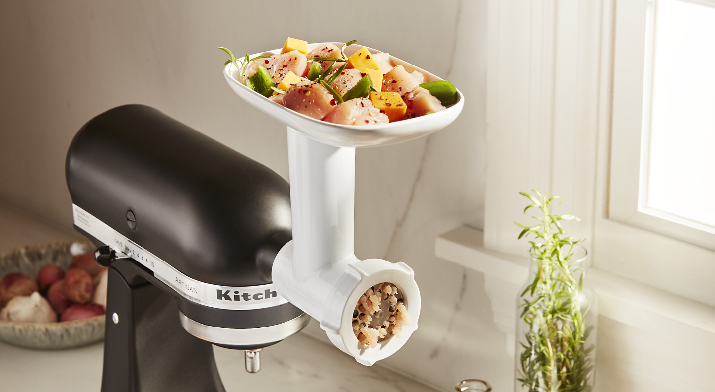 Chicken and vegetables in tray of KitchenAid® Food Grinder attachment.