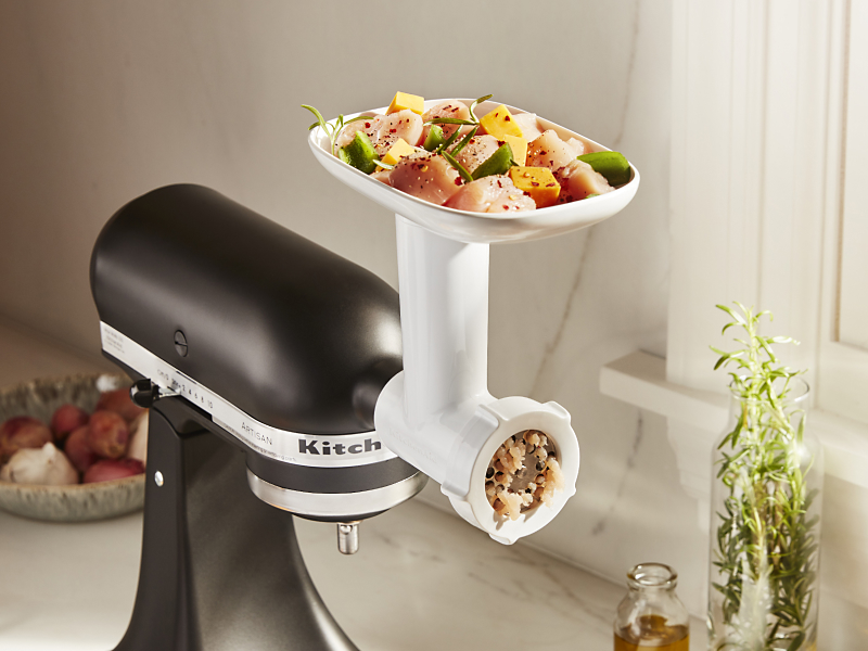 Chicken and vegetables in tray of KitchenAid® Food Grinder attachment.