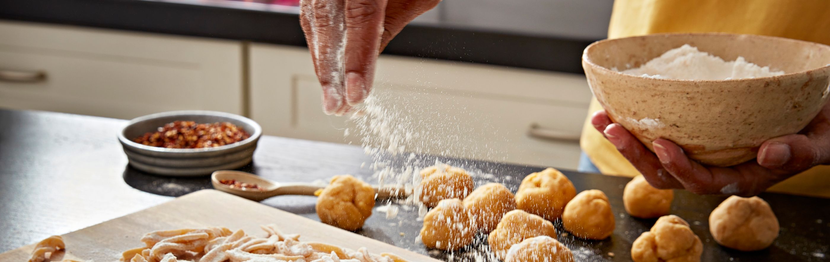 A person sprinkling flour over dough