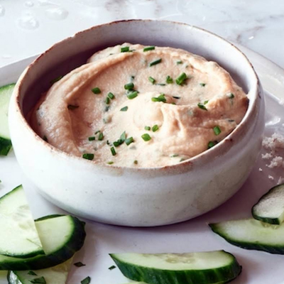 Zesty white bean dip in a bowl with cucumbers on the side
